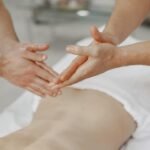 Hands of a masseur applying oil during a relaxing massage therapy session indoors.